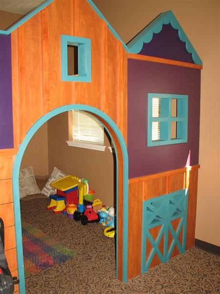 a play room with a blue and purple house with toys