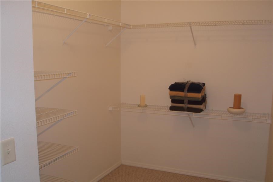 a walk in closet with a suitcase on a shelf