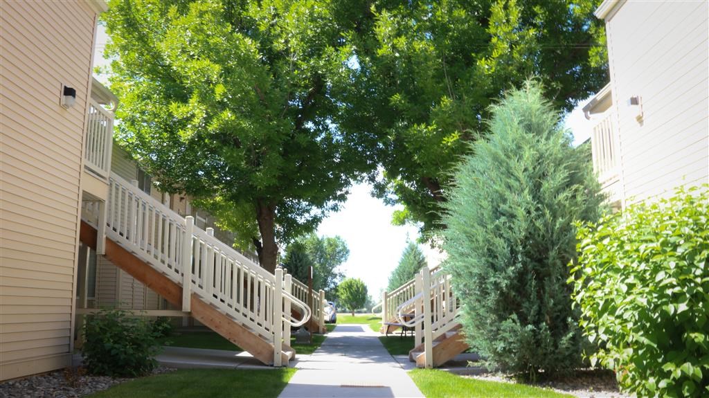 a sidewalk between two buildings with trees