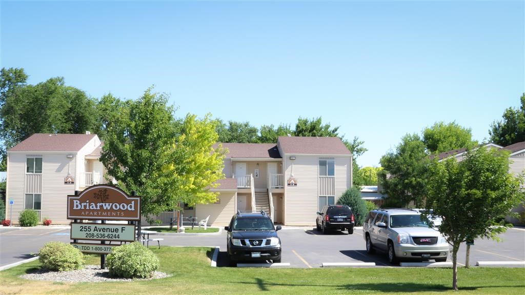 a parking lot with cars in front of a barwood apartments building