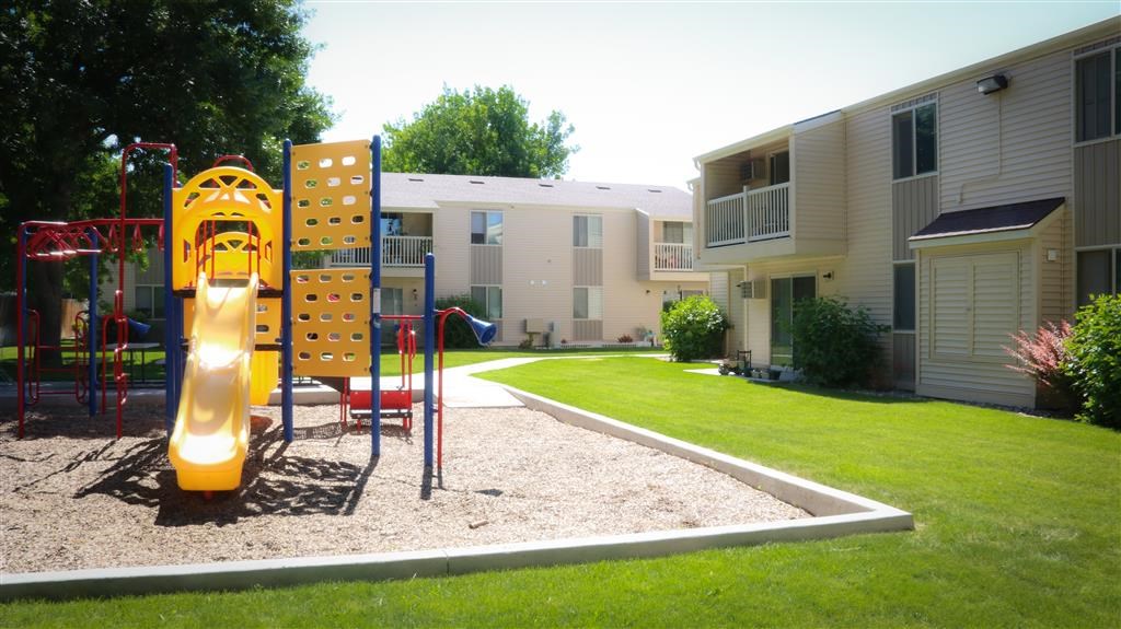 a playground with a slide in front of an apartment building