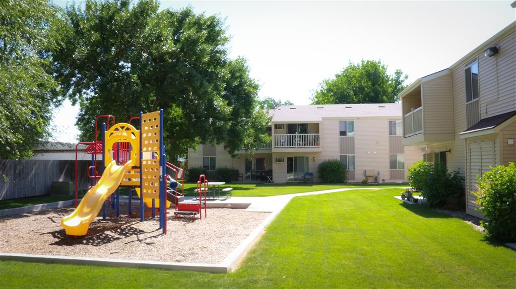 a playground in a yard in front of an apartment building