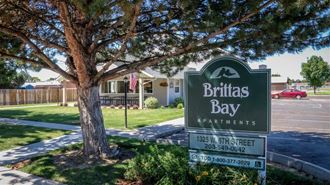 a sign for britas bay apartments in front of a tree