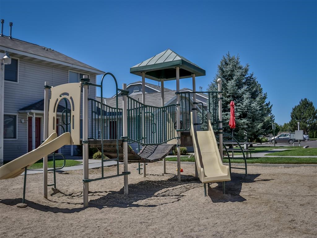 a playground with a slide and climbing equipment in front of a house
