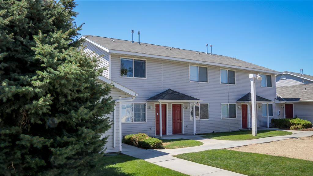 a white house with red doors and a tree