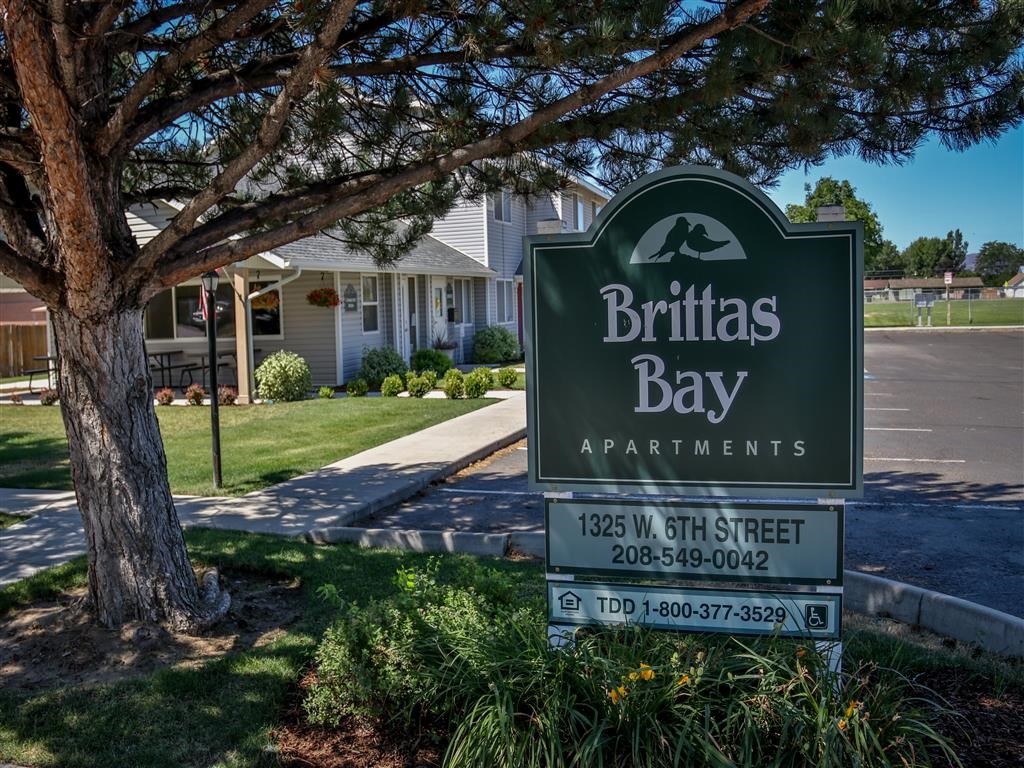 a sign for britas bay apartments in front of a tree