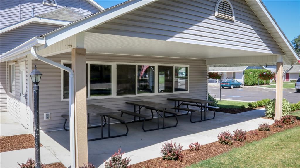 a covered patio with picnic tables in front of a house