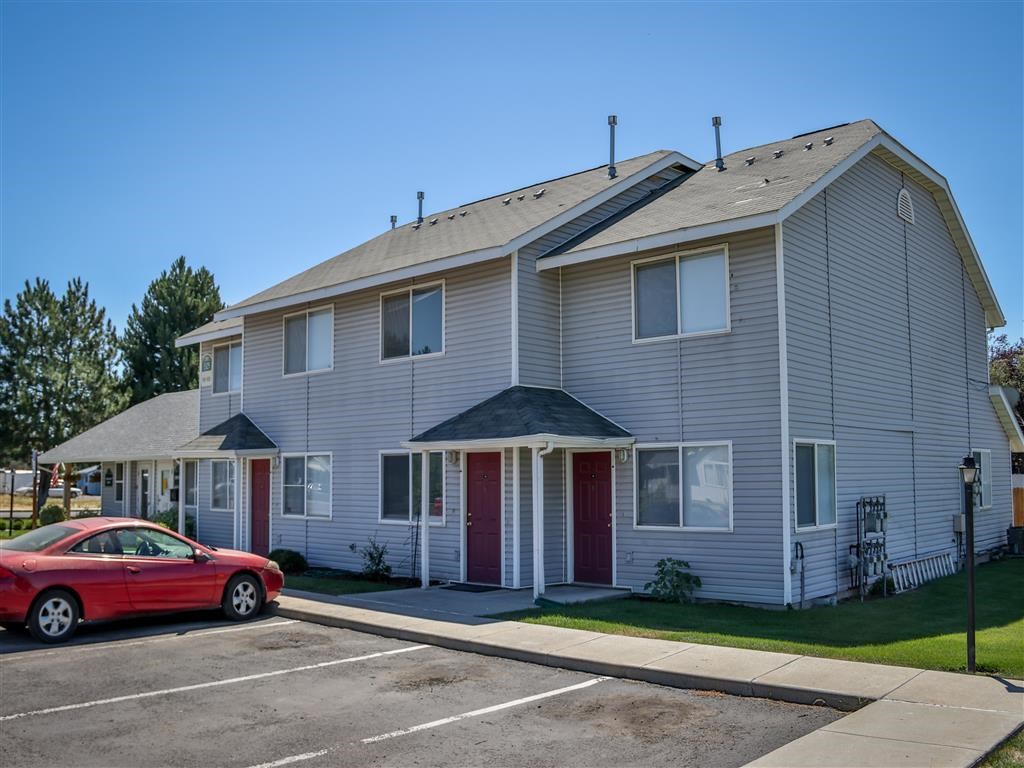 a white apartment building with a red car parked in front