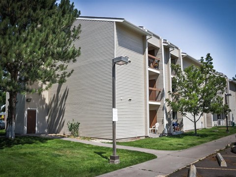 an apartment building with stairs and a tree in front of it