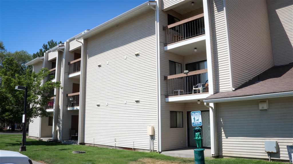 an apartment building with white siding and a green pole