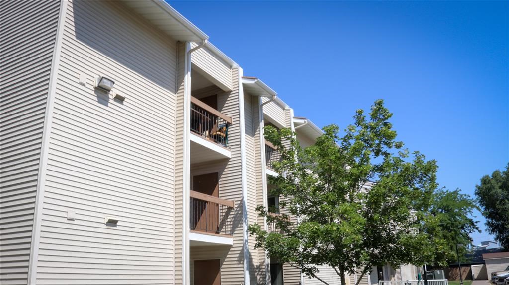 a white apartment building with balconies and a tree
