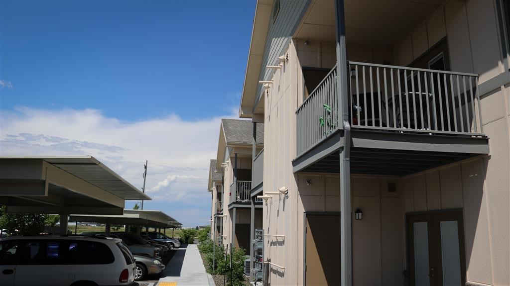 a building with a balcony and cars parked outside of it