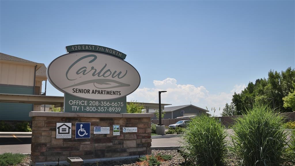 a sign for carlow school apartments in front of a parking lot
