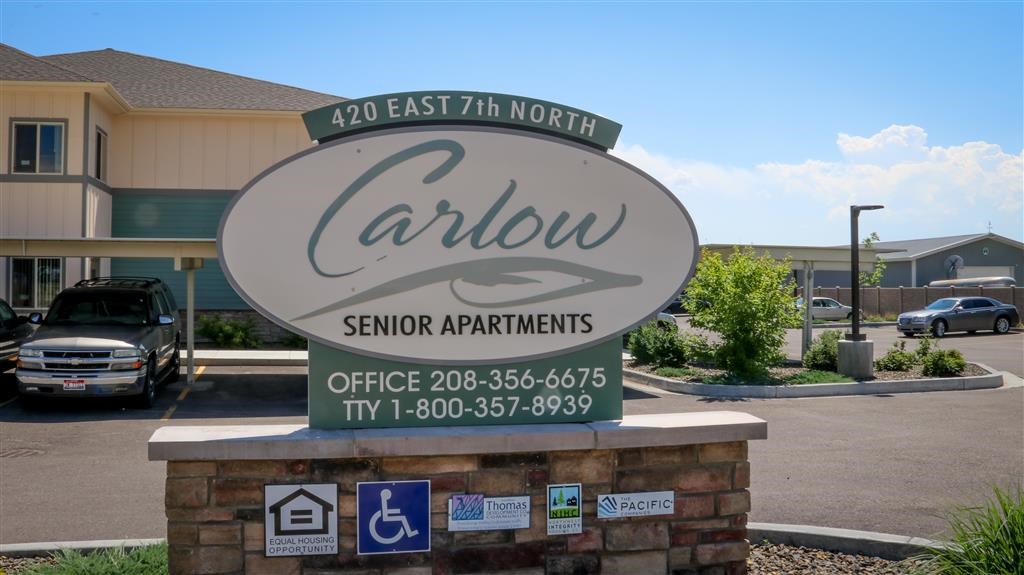 a sign for carlow senior apartments in front of a parking lot