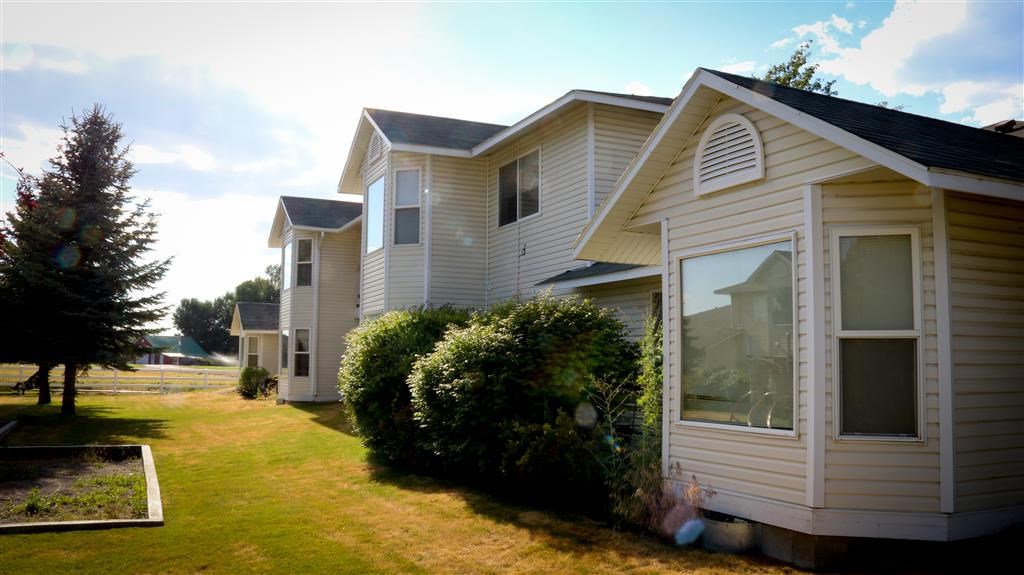 a row of houses with a lawn and trees