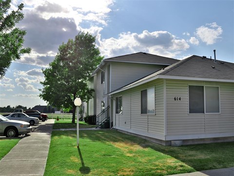 a white house with a yard and cars parked in a parking lot