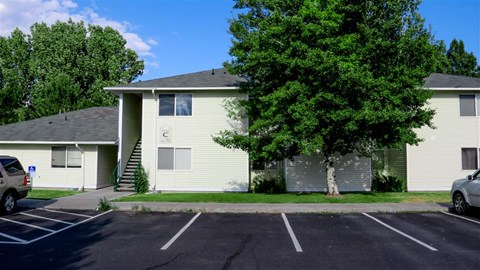 a white house with a tree in a parking lot