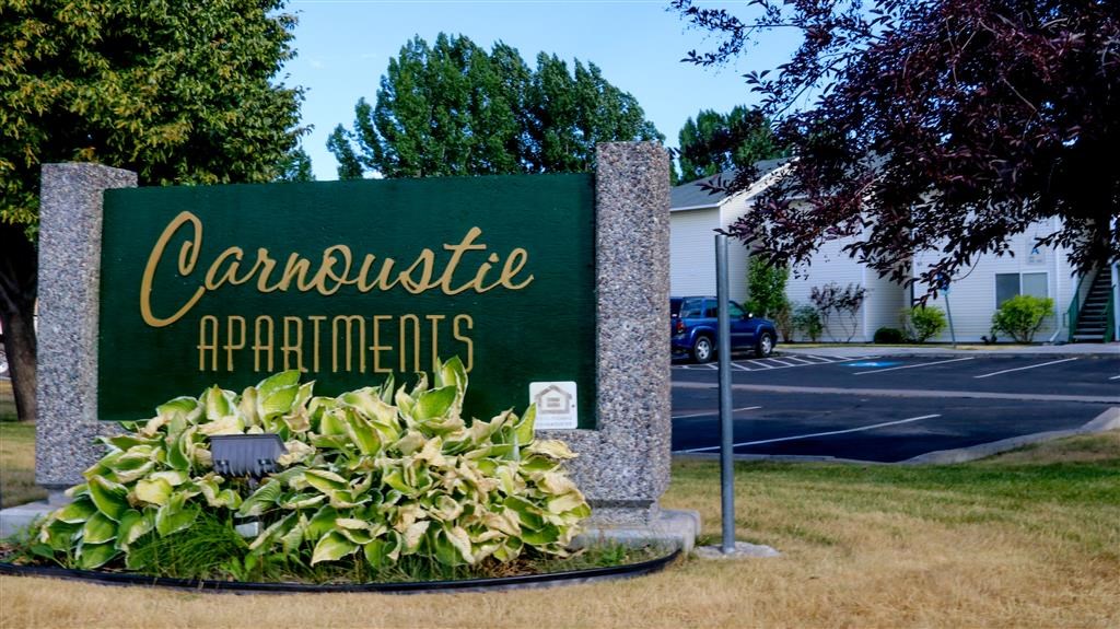 a sign for the carousel apartments on the side of a street