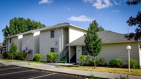 a white house with a sidewalk and trees in front of it