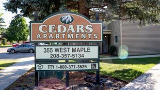 a sign for cedars apartments in front of a house