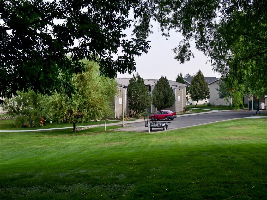a park with a red car parked in front of houses