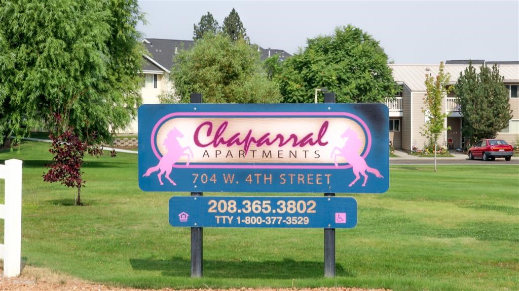 a sign for the apartments in front of a lawn