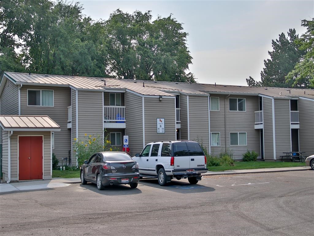 an apartment building with cars parked in a parking lot