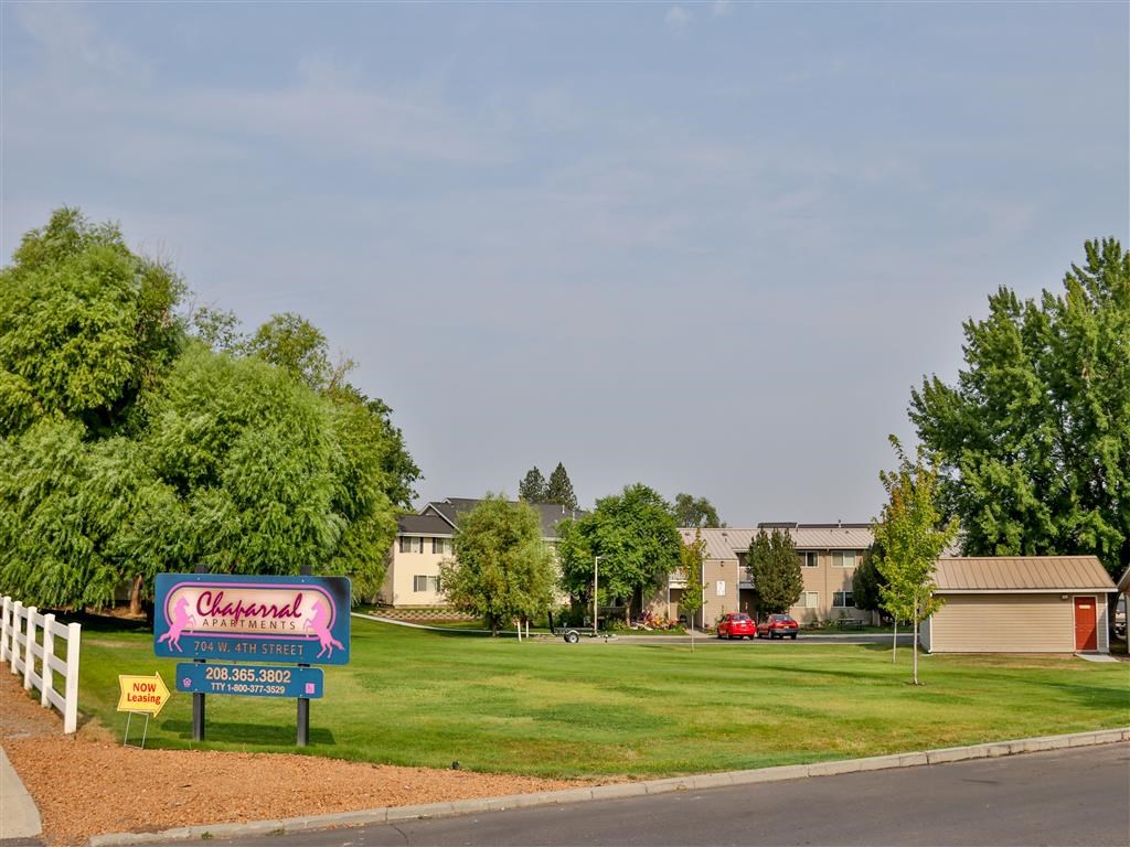 a sign in front of a green lawn with houses