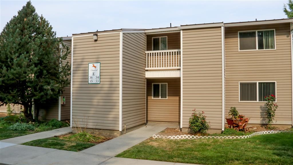 an apartment building with a porch and a sidewalk