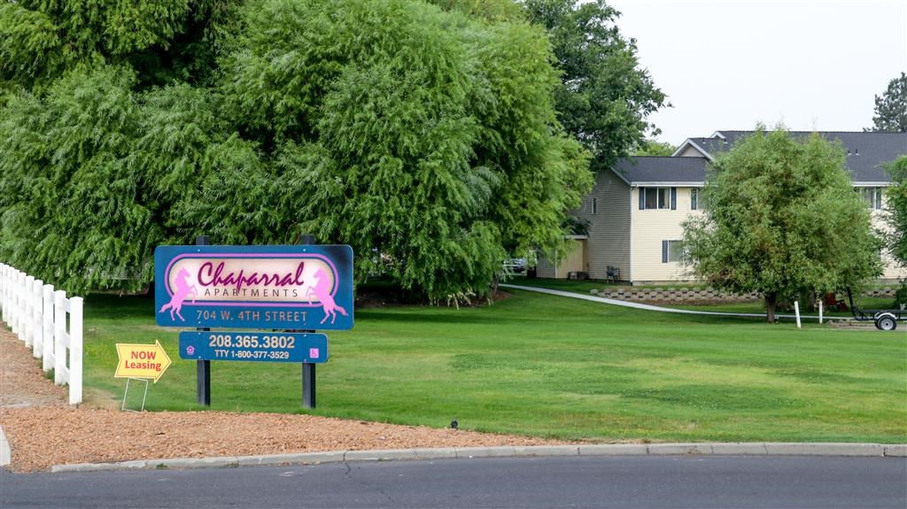 a sign on the side of the street in front of a lawn