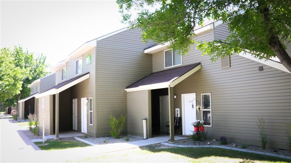 the front of a gray house with a white door