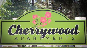 a sign for chewywood apartments with pink flowers on it