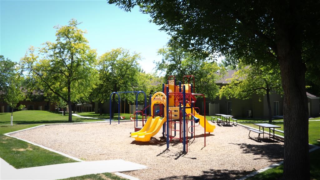 a playground with a yellow swing set in a park