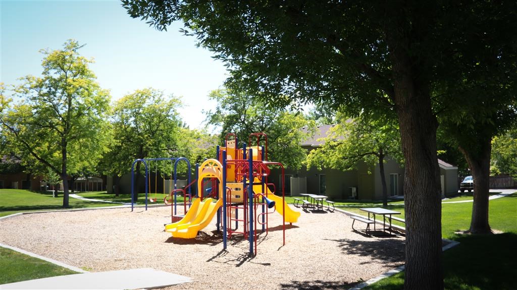 a playground with a yellow swing set in a park