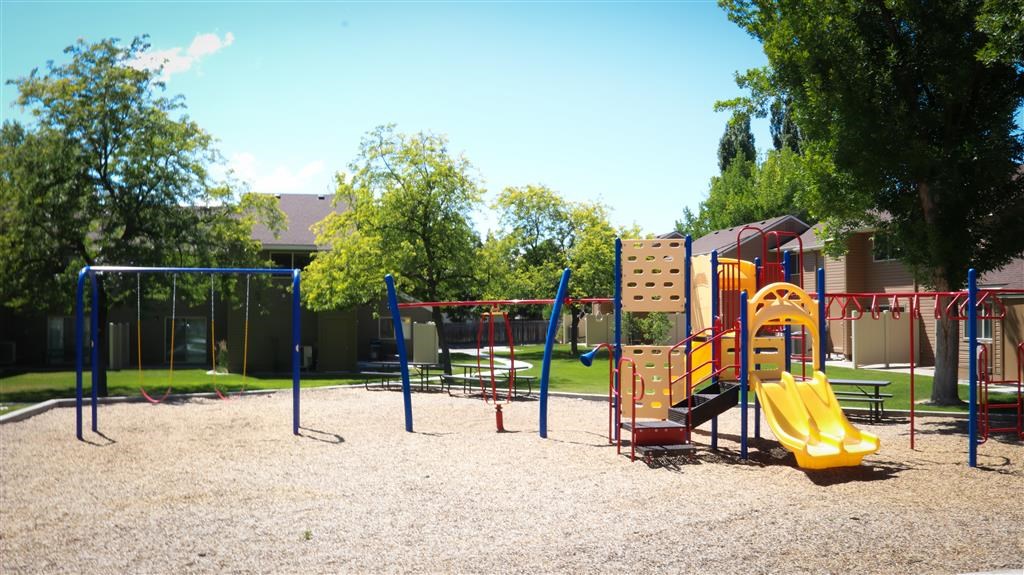 a playground with a swing set and slides in a park