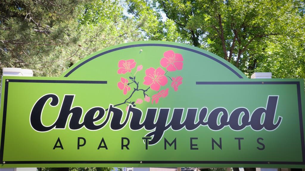 a sign for chewywood apartments in front of trees