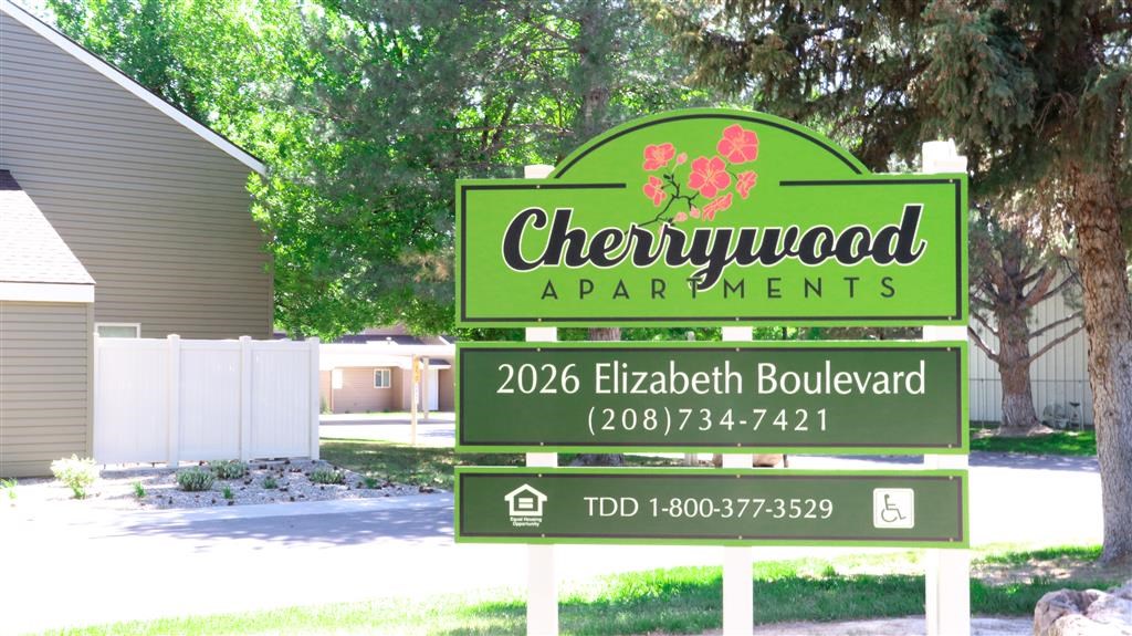 a sign for chewywood apartments in front of a yard