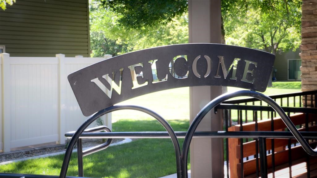 a welcome sign on a porch with a bench