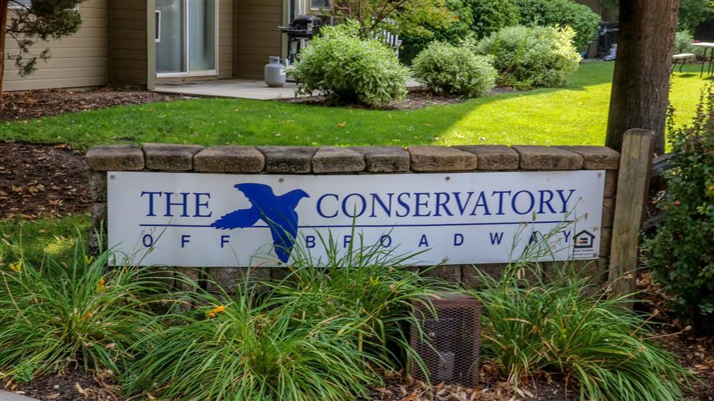 a sign for the conservatory of fenced in yard in front of a house