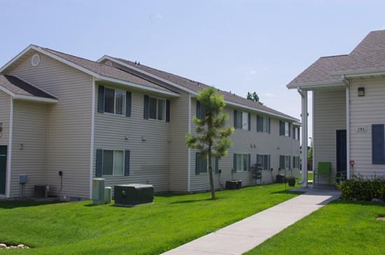 a row of white houses with a sidewalk and grass