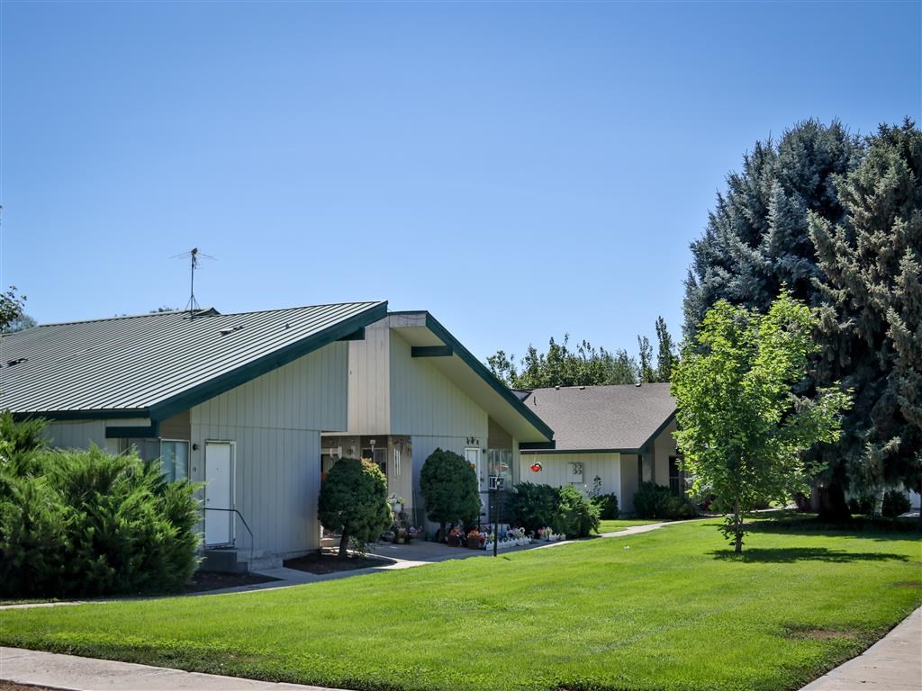 a white house with a green lawn and trees