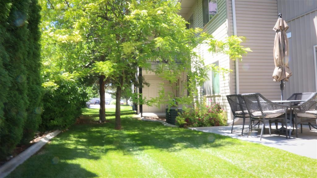 a patio with a table and chairs on a lawn