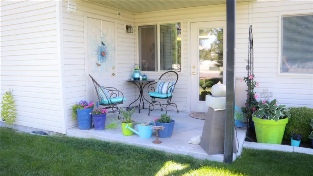 a porch with two chairs and potted plants on it