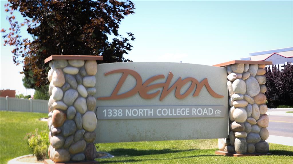 a sign for the delon north college road in front of a tree