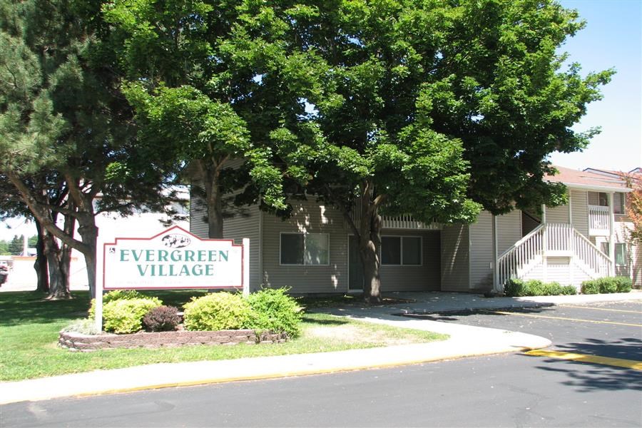 a sign for the evergreen village in front of a building