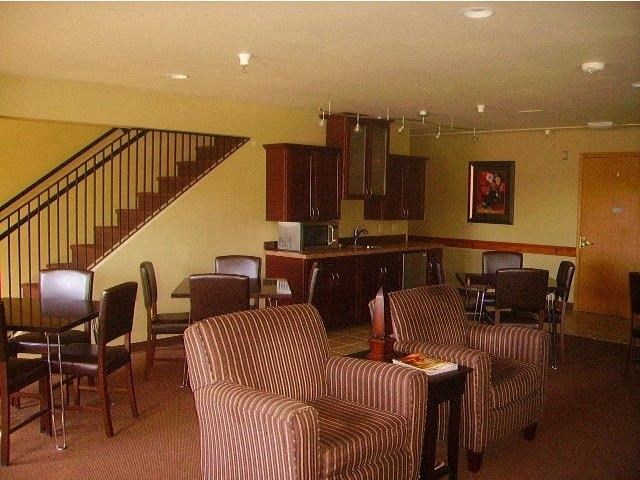 a living room with chairs and a table and a staircase