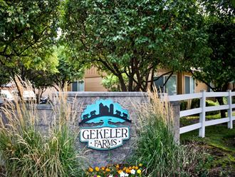 a sign for geller farms in front of a fence and trees