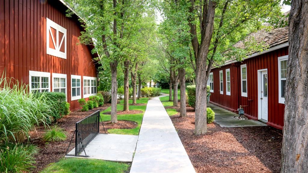 a sidewalk in front of a red building with trees