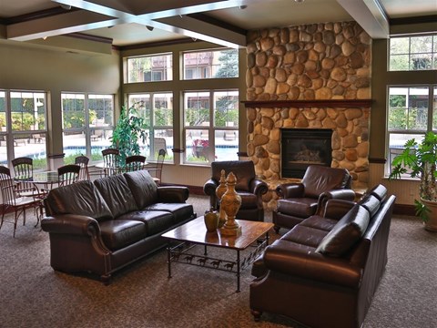 a large living room with leather furniture and a stone fireplace