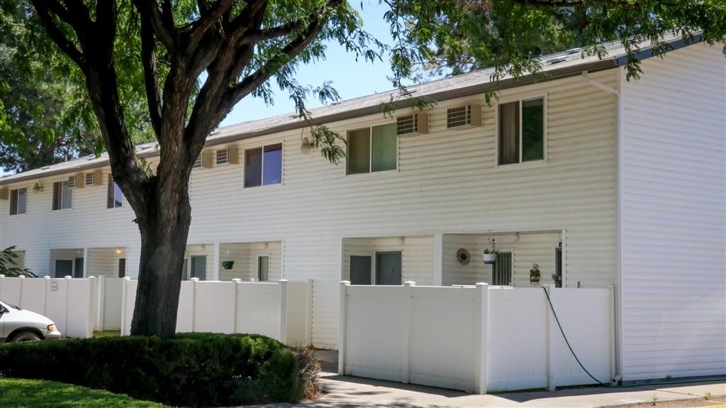 a white house with a tree and a white fence